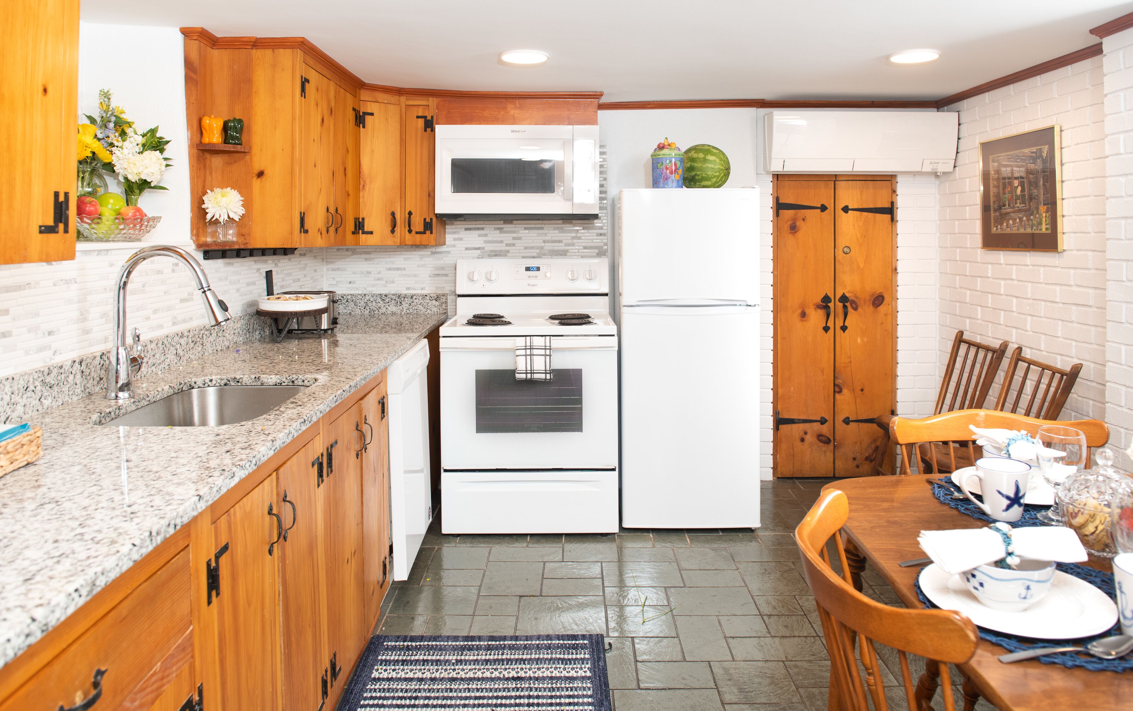 A kitchen with wooden cabinets, a granite countertop, a microwave, a stove, and a refrigerator.