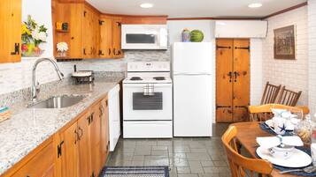 A kitchen with wooden cabinets, a granite countertop, a microwave, a stove, and a refrigerator.