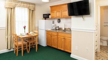 A compact kitchen with wooden cabinets, a built-in microwave, a coffee maker, and a sink.