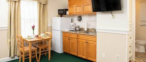 A compact kitchen with wooden cabinets, a built-in microwave, a coffee maker, and a sink.