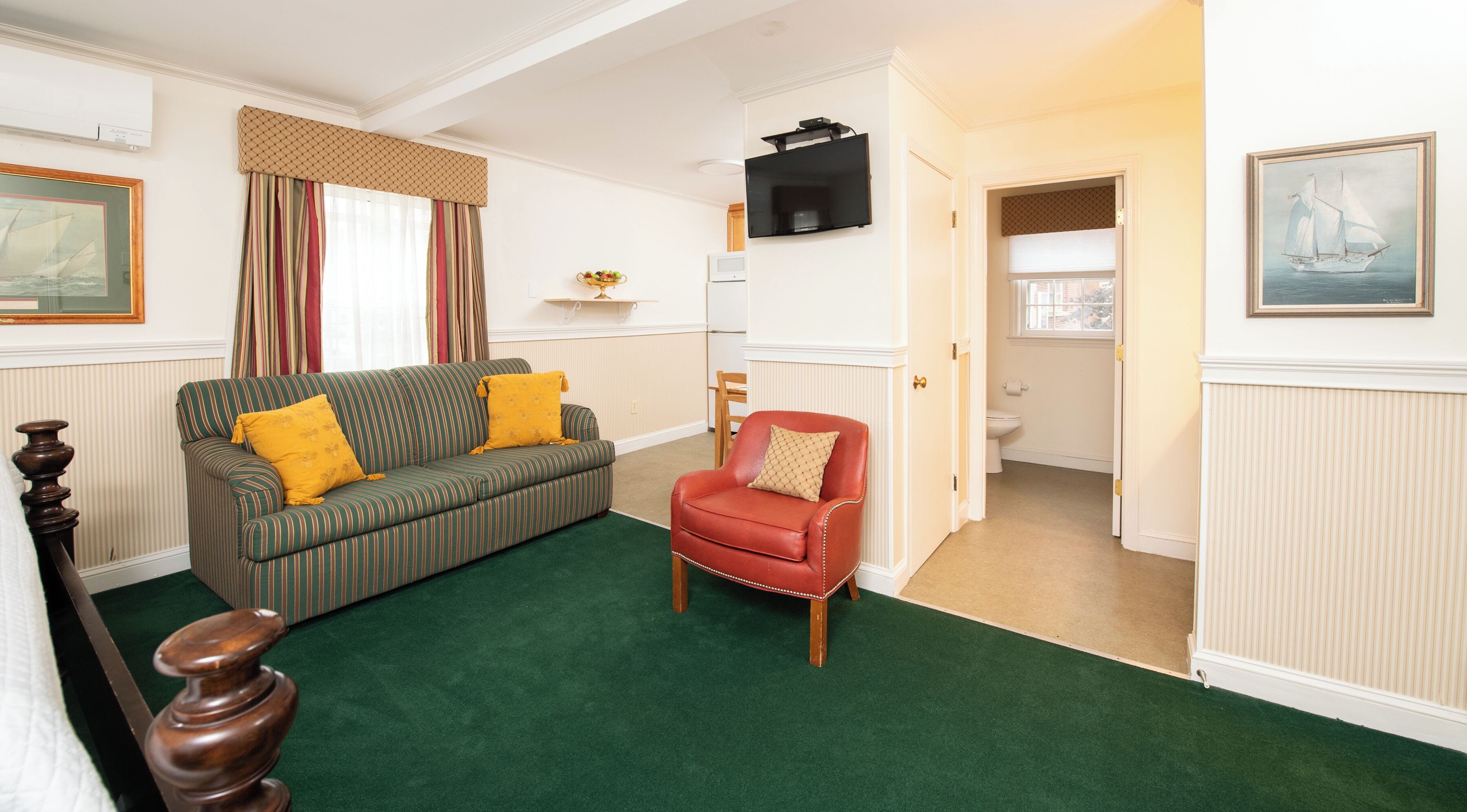 A living room with a green sofa, a red armchair, and a green carpet.