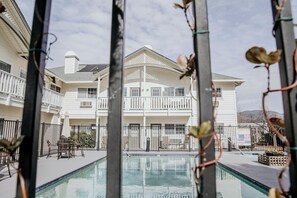 A pool area with a view of a white building with balconies and a covered patio.