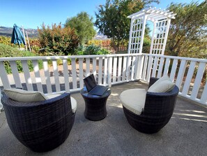 A patio with wicker furniture, a laptop, and a pergola.