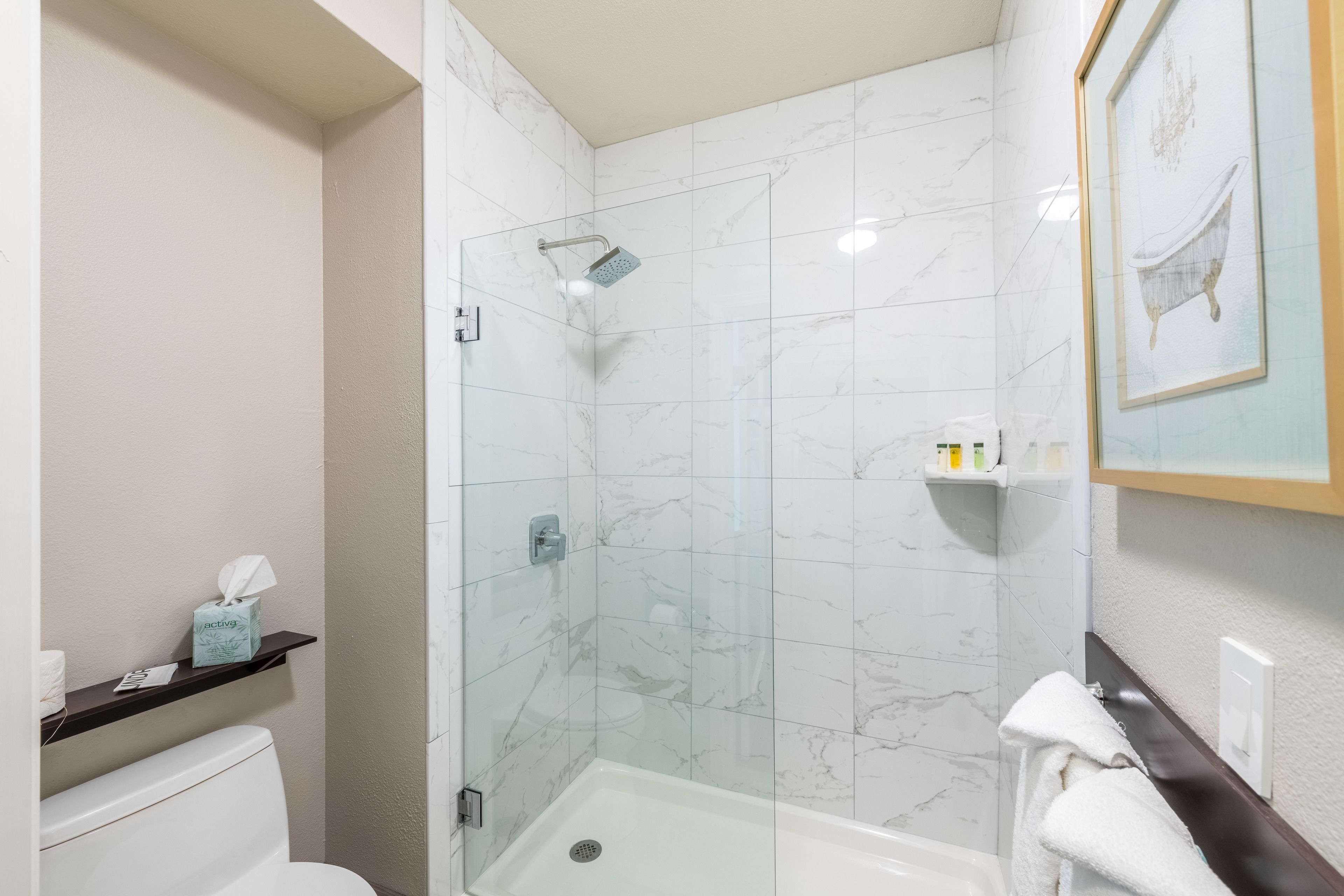 Un baño moderno con ducha de vidrio, inodoro blanco y toallero.