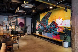 A modern interior with a large mural, seating areas, and a reception desk.