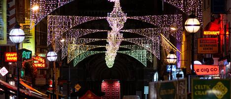 A busy street at night with illuminated arches and a large chandelier.