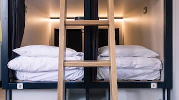 Een stapelbed met een houten ladder, wit beddengoed en een zwart metalen frame.