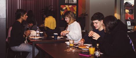 A group of people dining at a restaurant with a neon sign reading '#I'MIN DUBLIN' and a poster of the Empire State Building.