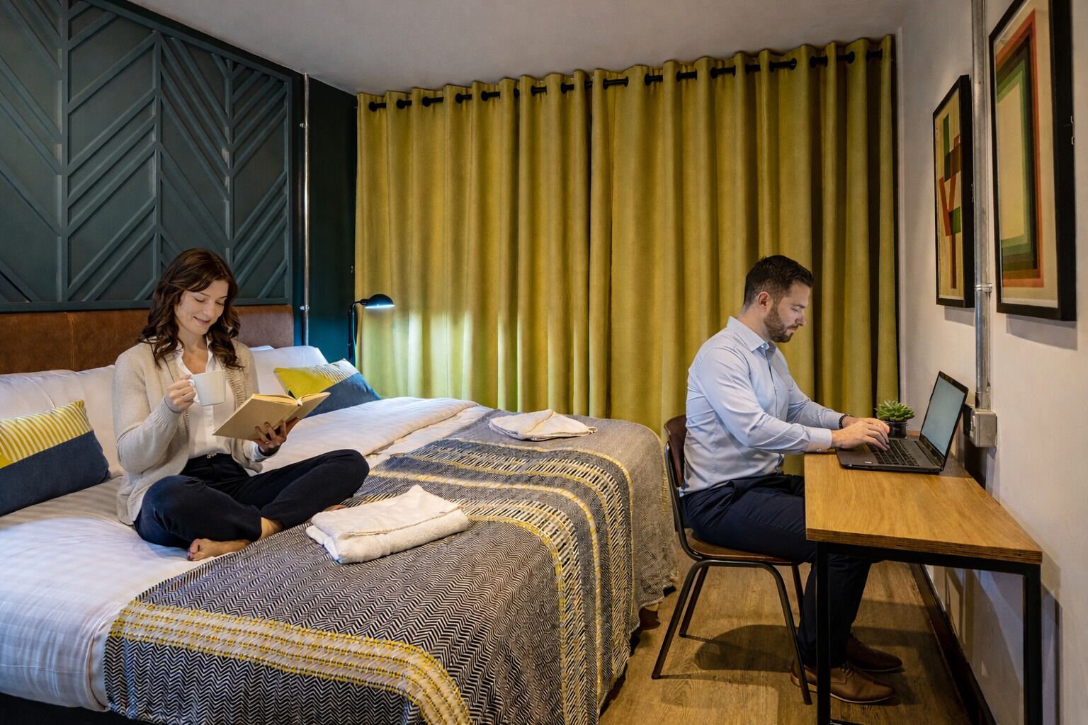 Habitación de hotel con dos camas, un escritorio y una computadora portátil.