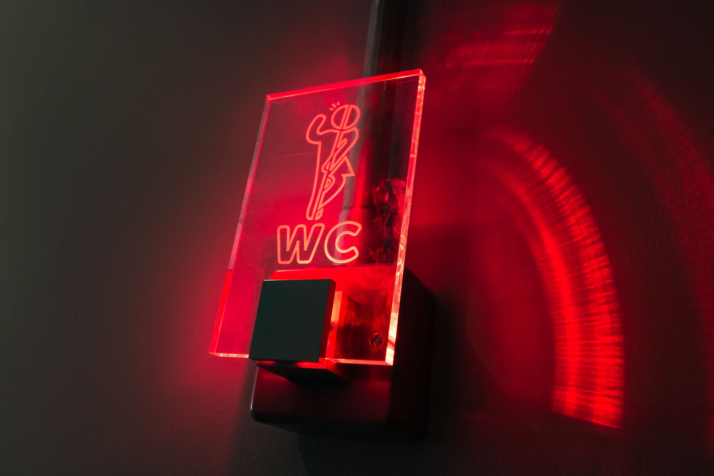 A restroom sign with a neon light.