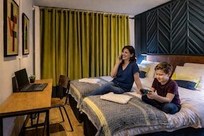 A hotel room with two beds, a desk, a laptop, and a green curtain. - Latroupe Jacobs Inn (Dublin)