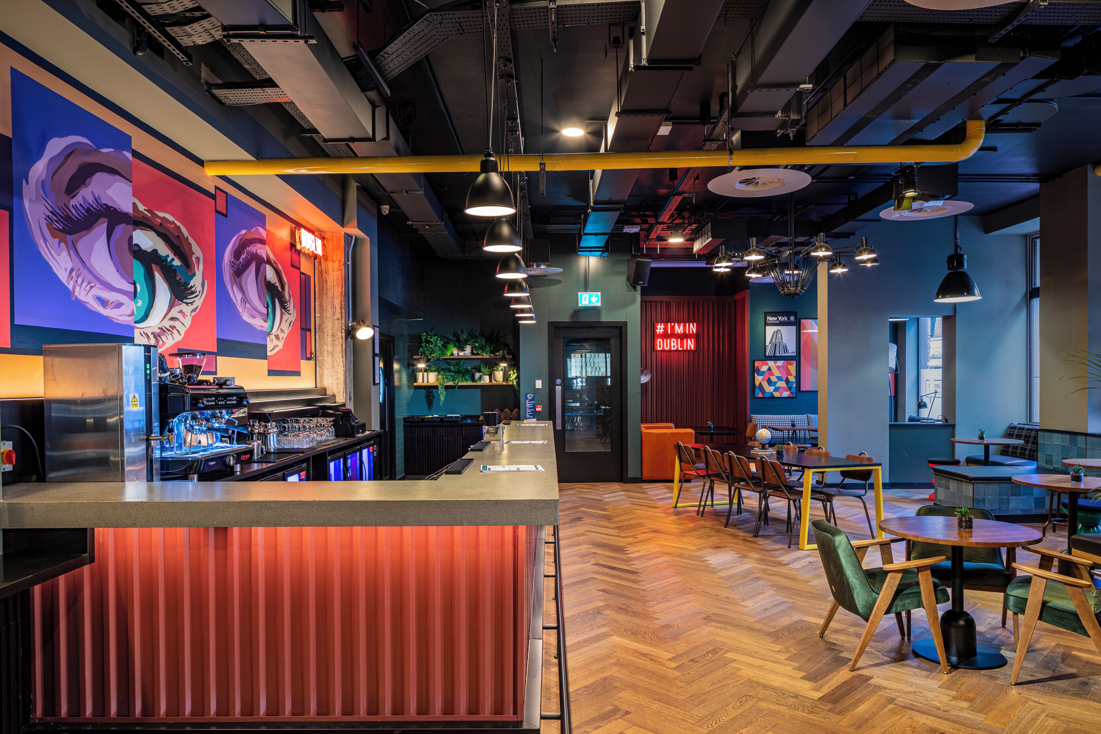 Un'area bar moderna con un bancone, sgabelli e una zona salotto con tavoli e sedie.
