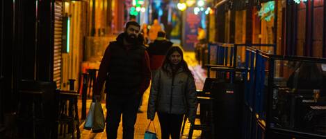 A nighttime street scene with illuminated signs and a wet pavement reflecting lights.
