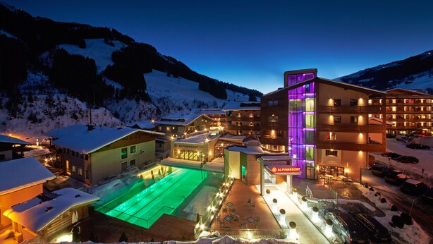 Um hotel com vários edifícios, área de piscina e arredores cobertos de neve.