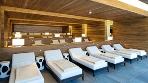 Uma área de spa com vários espreguiçadeiras, teto de madeira e um espaço de estar com luminárias.