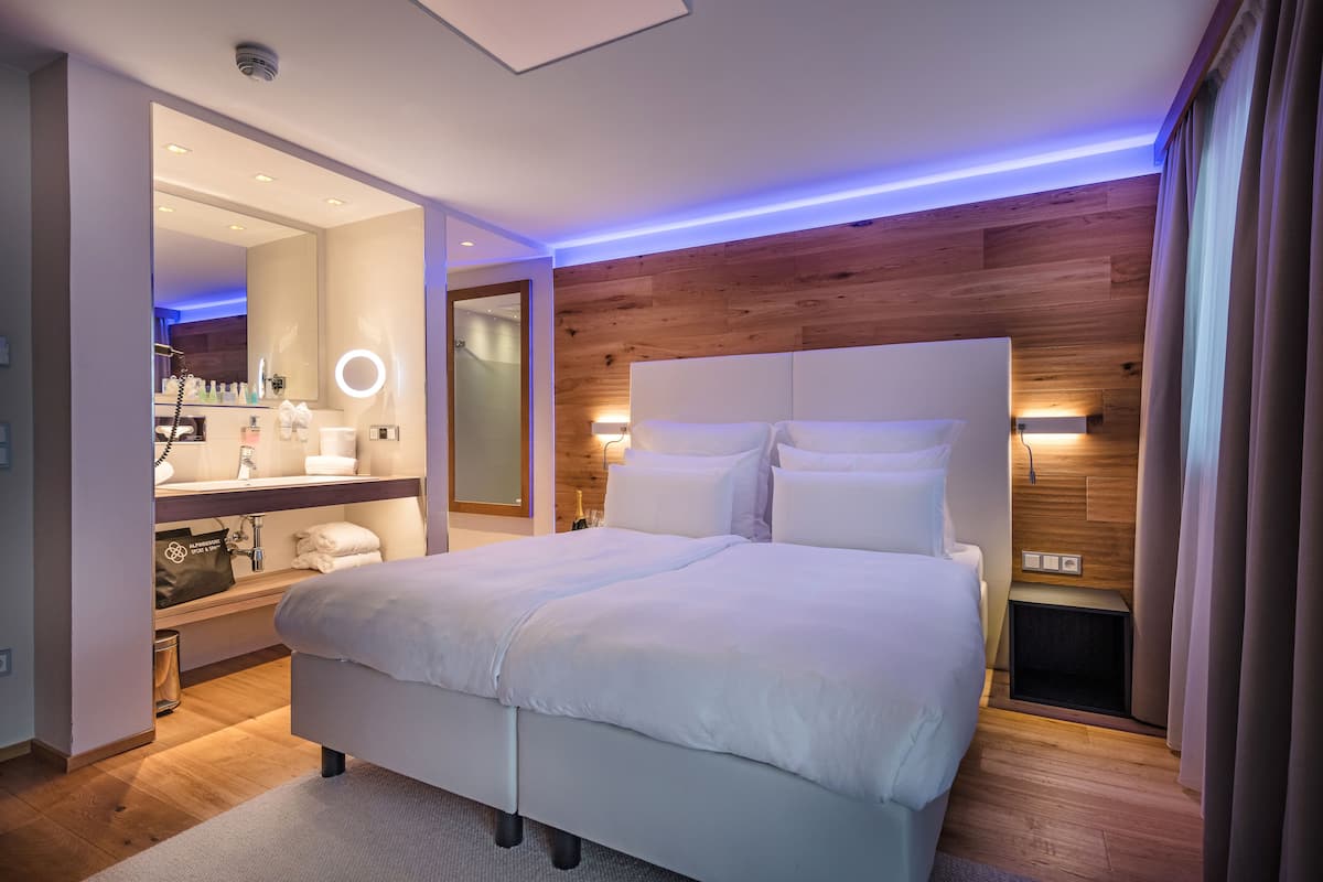 A modern bedroom with a large bed, a vanity with a mirror, and a wooden accent wall.