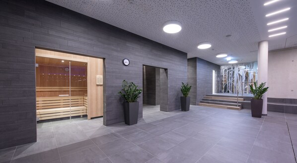 Um hall moderno com sauna, relógio e plantas em vasos.