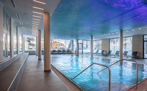 An indoor swimming pool with clear views of the outside, large windows, and a modern ceiling design. - Hotel Der Waldhof (Zell am See)