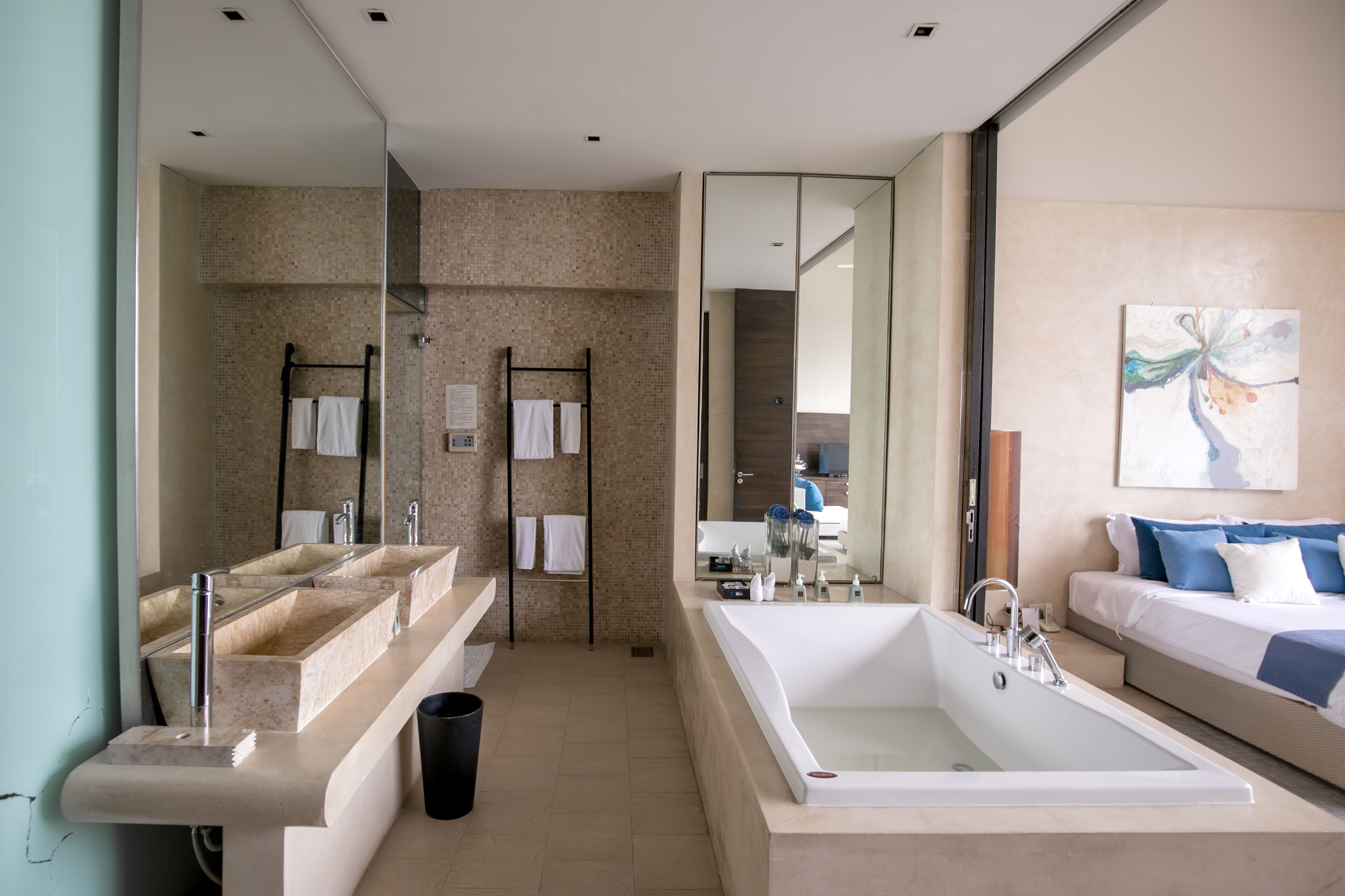 A modern bathroom with a large bathtub, dual sinks, and a mirror.
