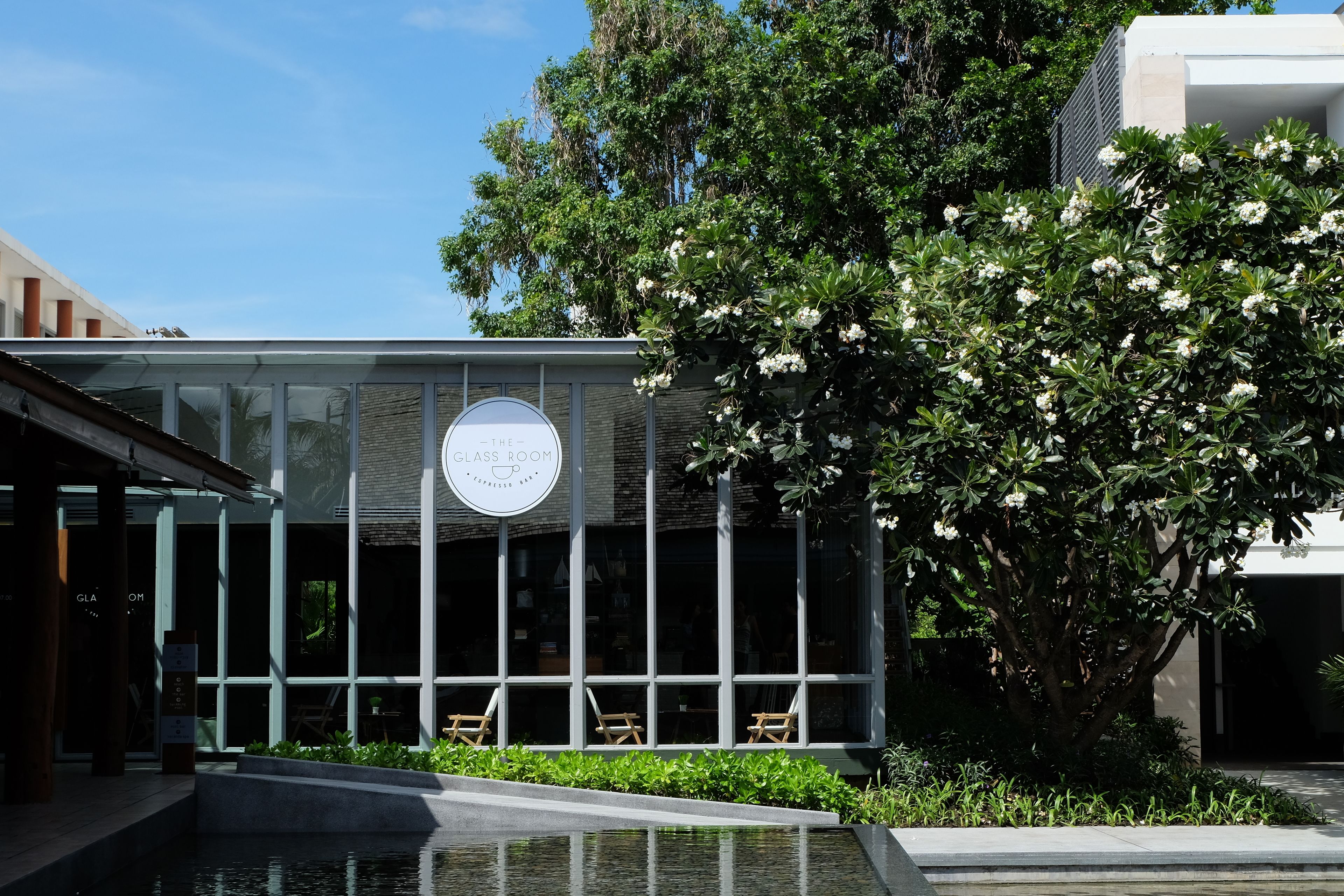 Un bâtiment moderne avec une façade en verre, une enseigne indiquant « THE CLASSROOM », et des sièges à l’extérieur.