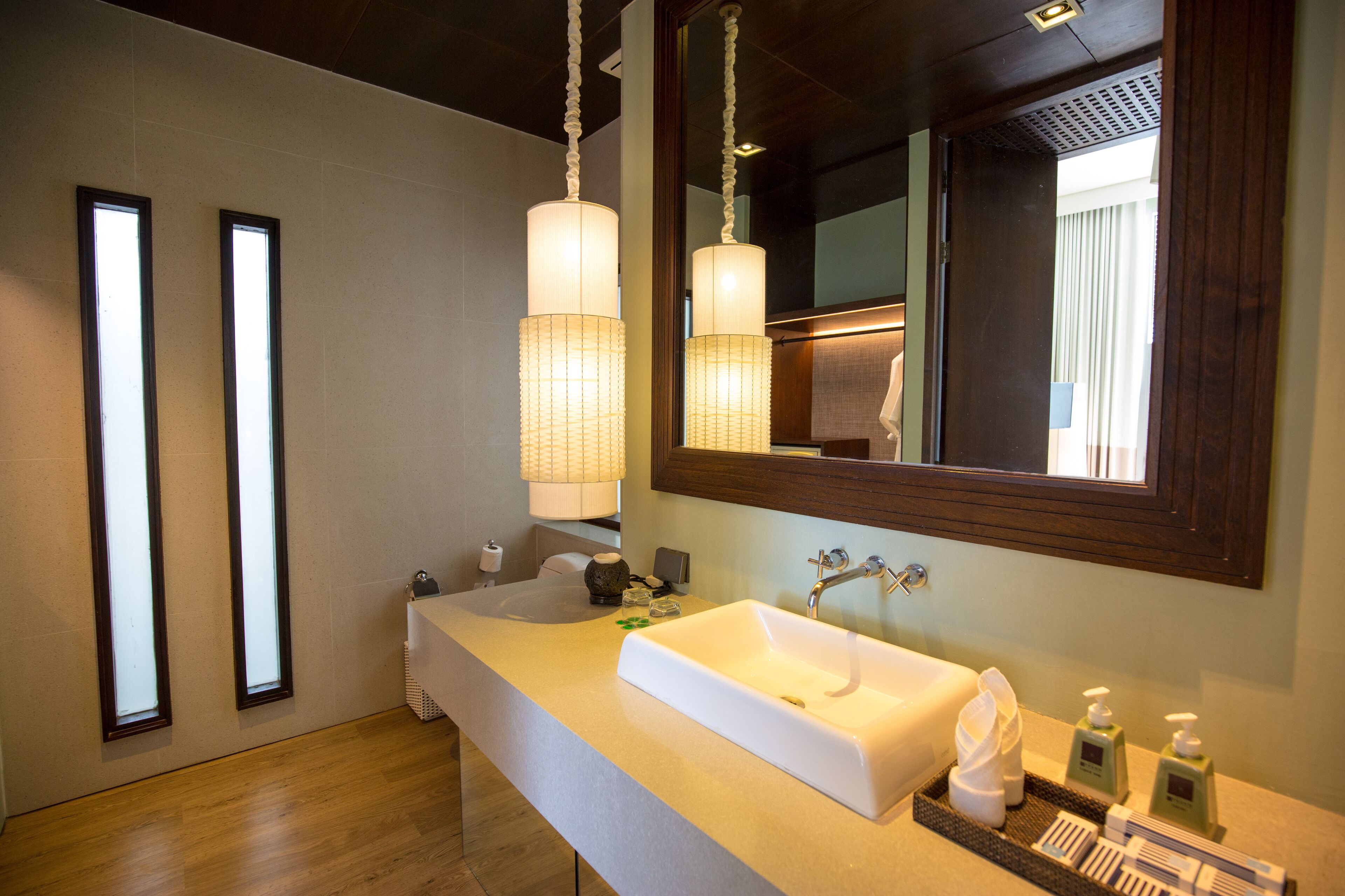 A modern bathroom with a large sink, mirror, and two pendant lights.