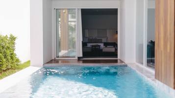 A modern indoor pool area with a clear view of a bedroom with a bed and a nightstand.