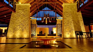 A spacious lobby with a high ceiling, stone pillars, and a central water feature.