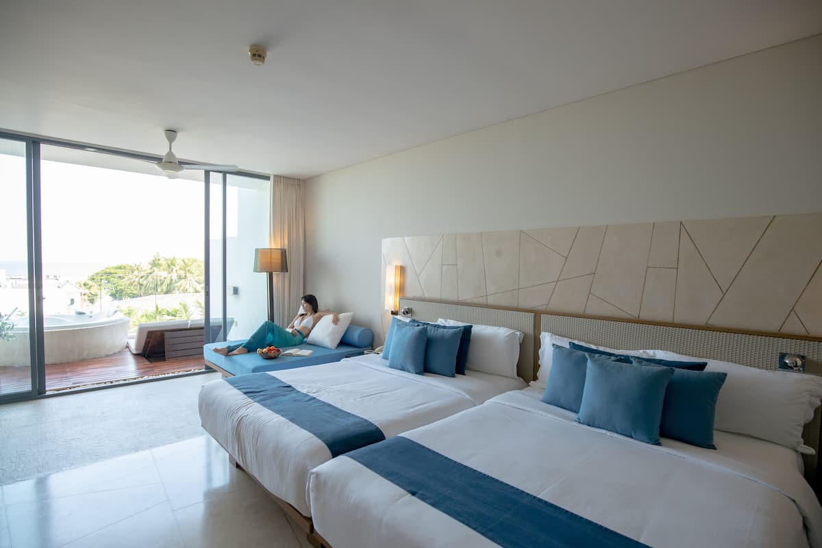 Ein Hotelzimmer mit zwei Betten, einem großen Fenster mit Blick, einem Deckenventilator und einer Lampe.