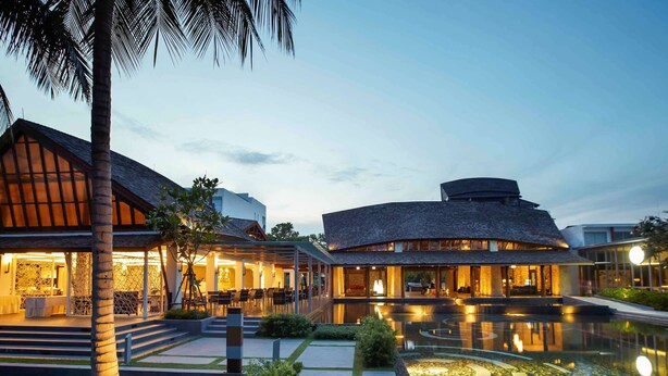 A resort with a pool, a covered outdoor dining area, and a building with a curved roof.