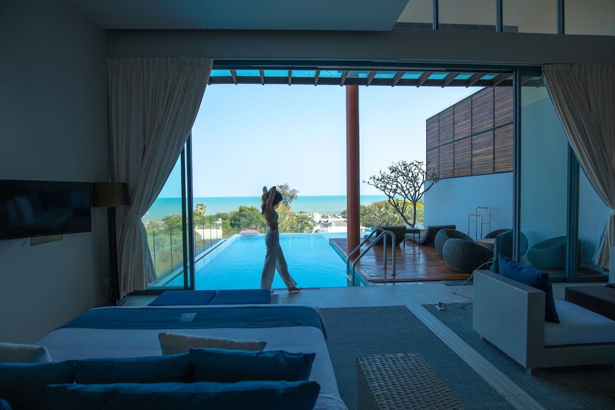 Ein modernes Hotelzimmer mit einem großen Bett, einem Fernseher und Blick auf einen Swimmingpool und den Ozean.