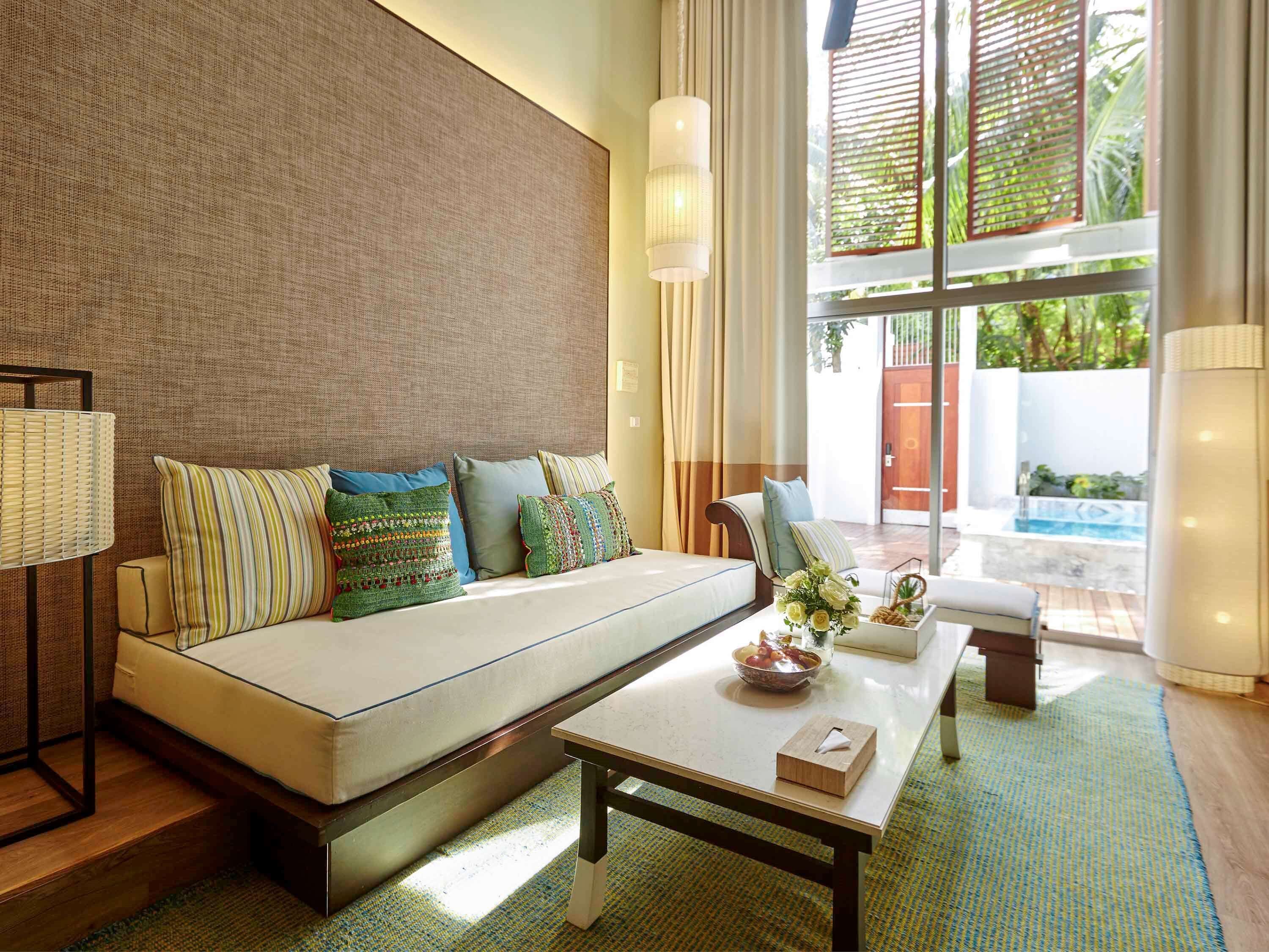 A modern living room with a sofa, a coffee table, and a view of a swimming pool.
