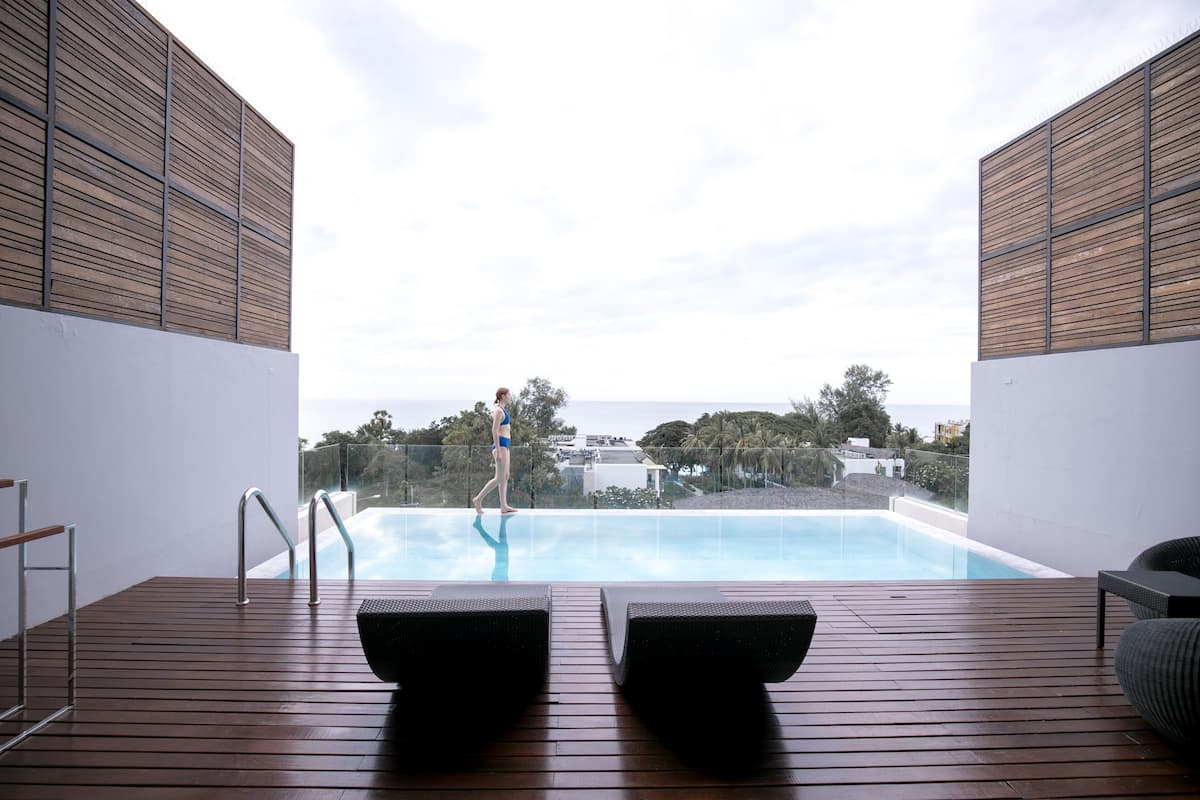 Ein Poolbereich mit Holzterrasse, Liegestühlen und Meerblick.