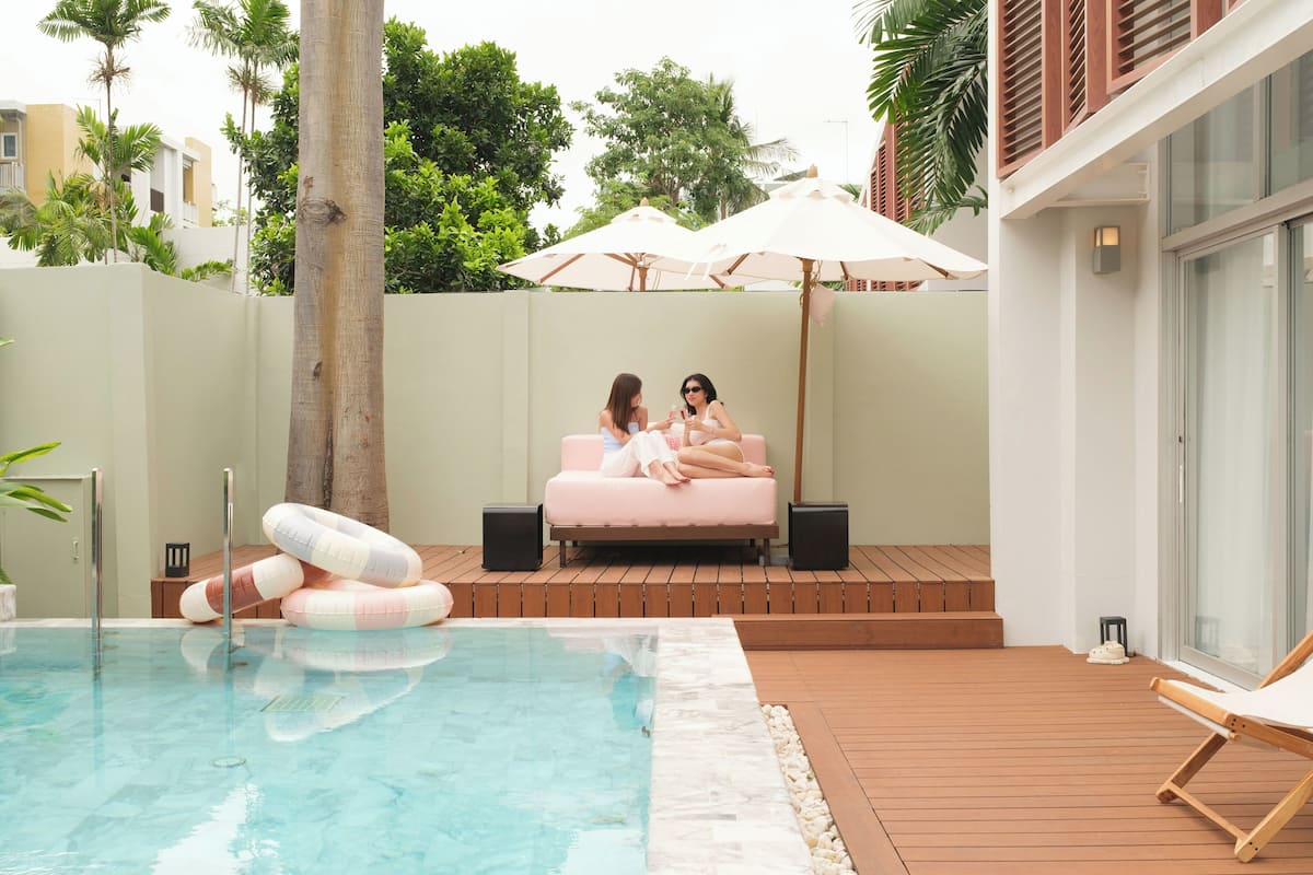 Ein Poolbereich mit Liegestühlen, einem rosa Sofa und Sonnenschirmen.