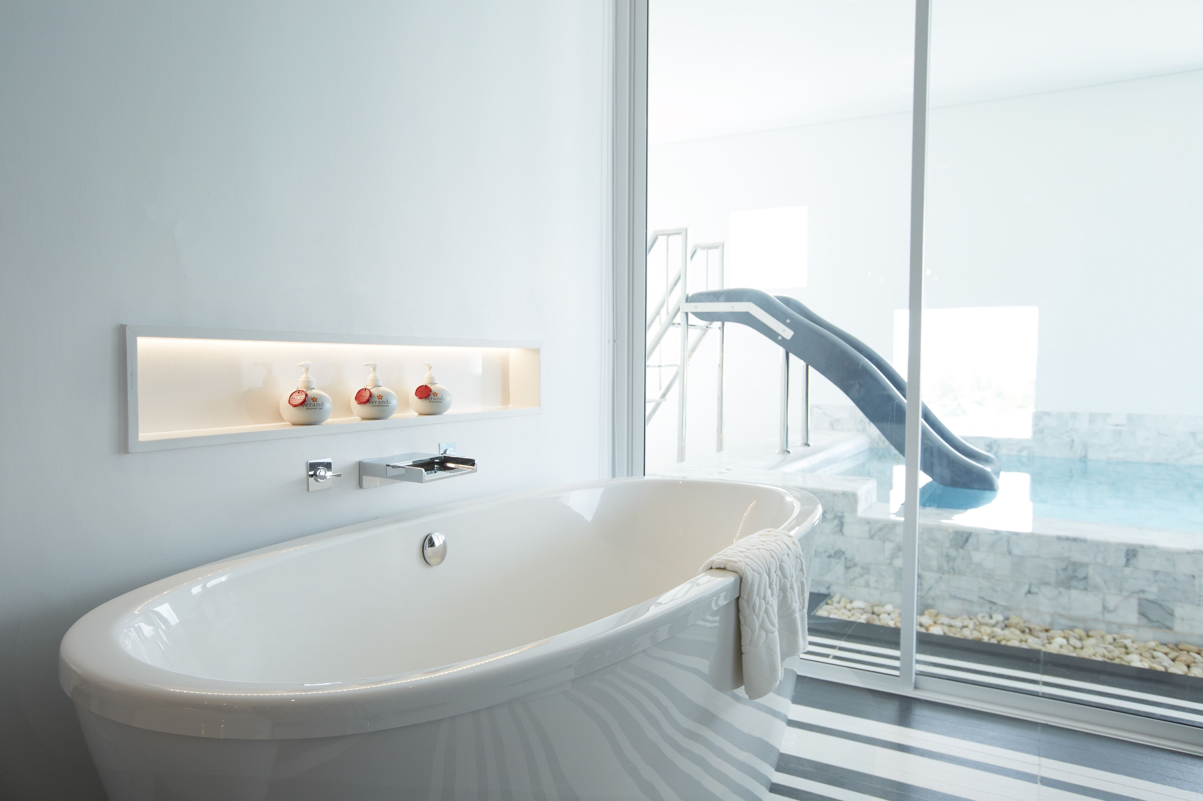 A modern bathroom with a freestanding bathtub, a glass shower enclosure, and a marble-tiled floor.