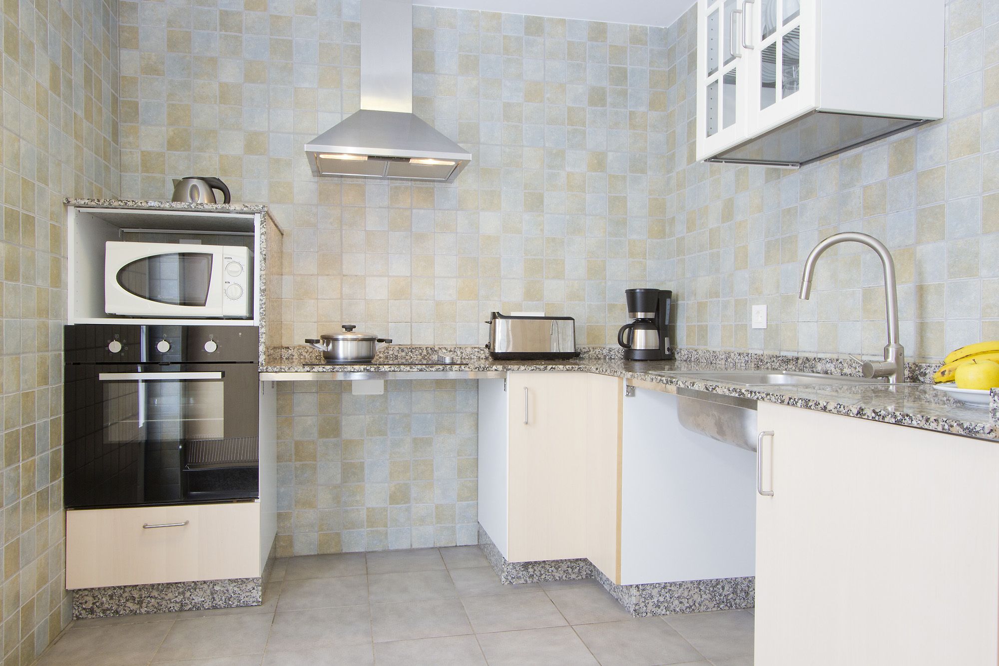 Una cocina equipada con microondas, horno, tostadora y cafetera.