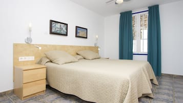 A bedroom with a bed, bedside tables, wall-mounted lamps, and a ceiling fan.