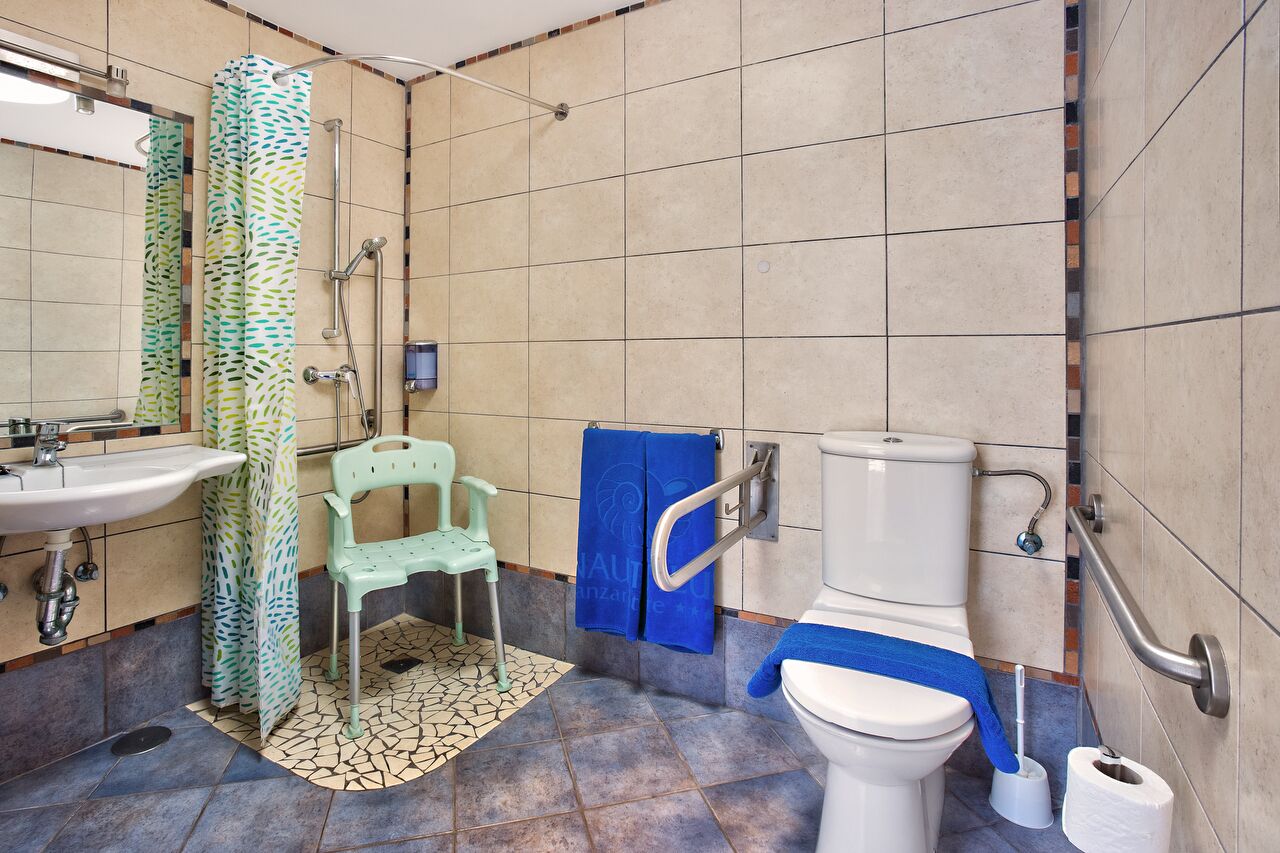 Ein Badezimmer mit Waschbecken, Toilette, Dusche und einem Stuhl.
