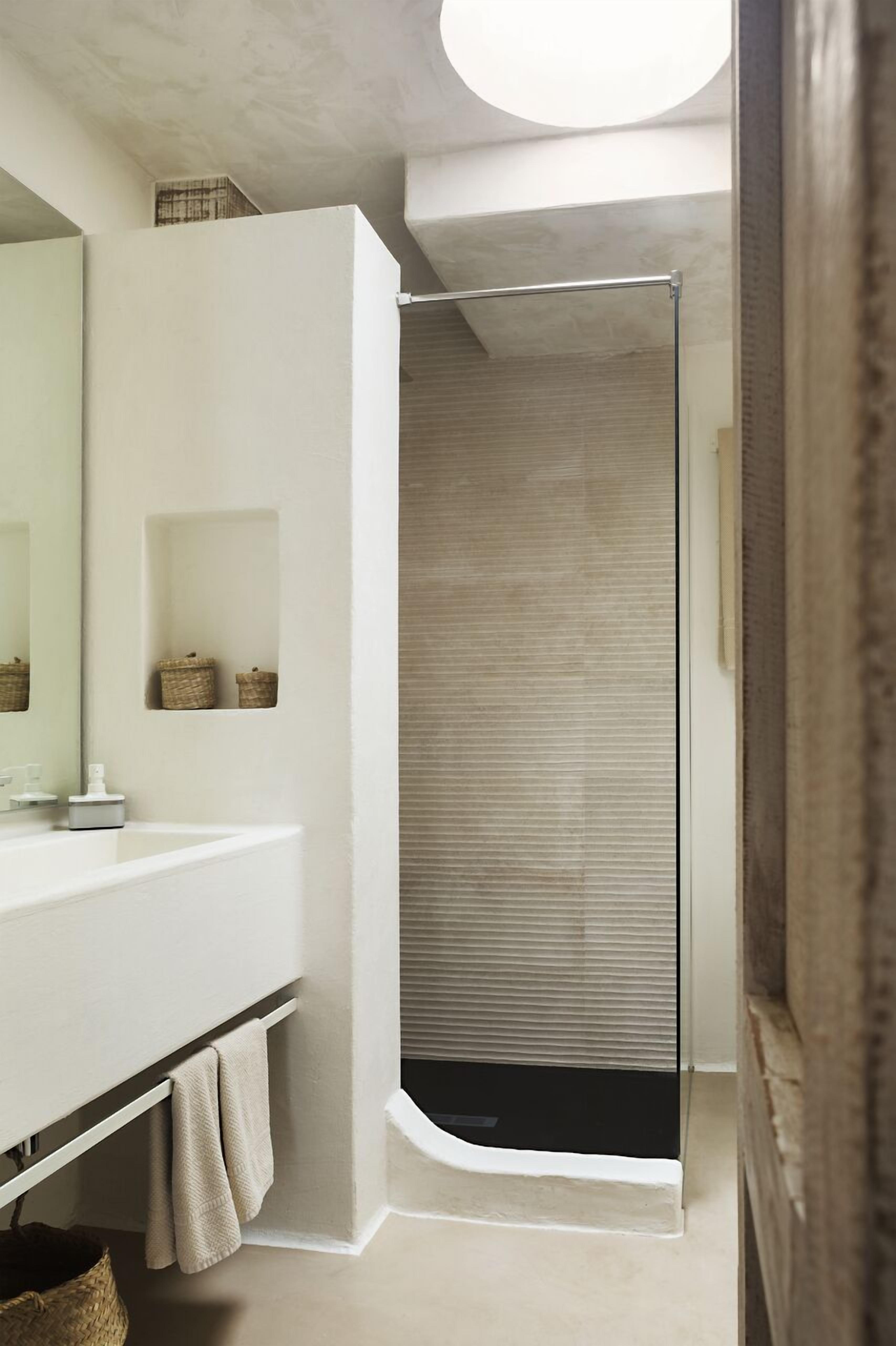 Une salle de bain avec un meuble-lavabo blanc, un miroir, un porte-serviettes et une cabine de douche.
