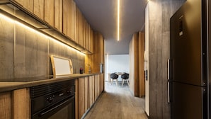 Una cocina moderna con armarios de madera, horno empotrado y refrigerador de acero inoxidable.