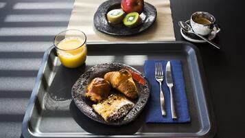 Een ontbijfwagen met croissants, een stukje taart en een glas sinaasappelsap.