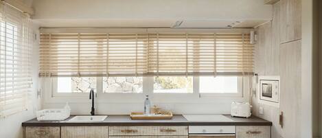 A modern kitchen with a large window, wooden cabinets, and a white countertop.