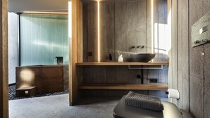 Un área de spa moderna con un mostrador de recepción de madera, una gran pila de piedra y una toalla sobre un banco.