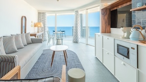 Un salón moderno con un sofá, una mesita y vista al mar.