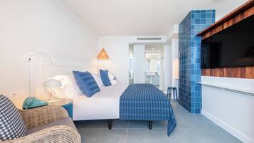 Una habitación de hotel moderna con cama, mesita de noche, lámpara y vista al pasillo.