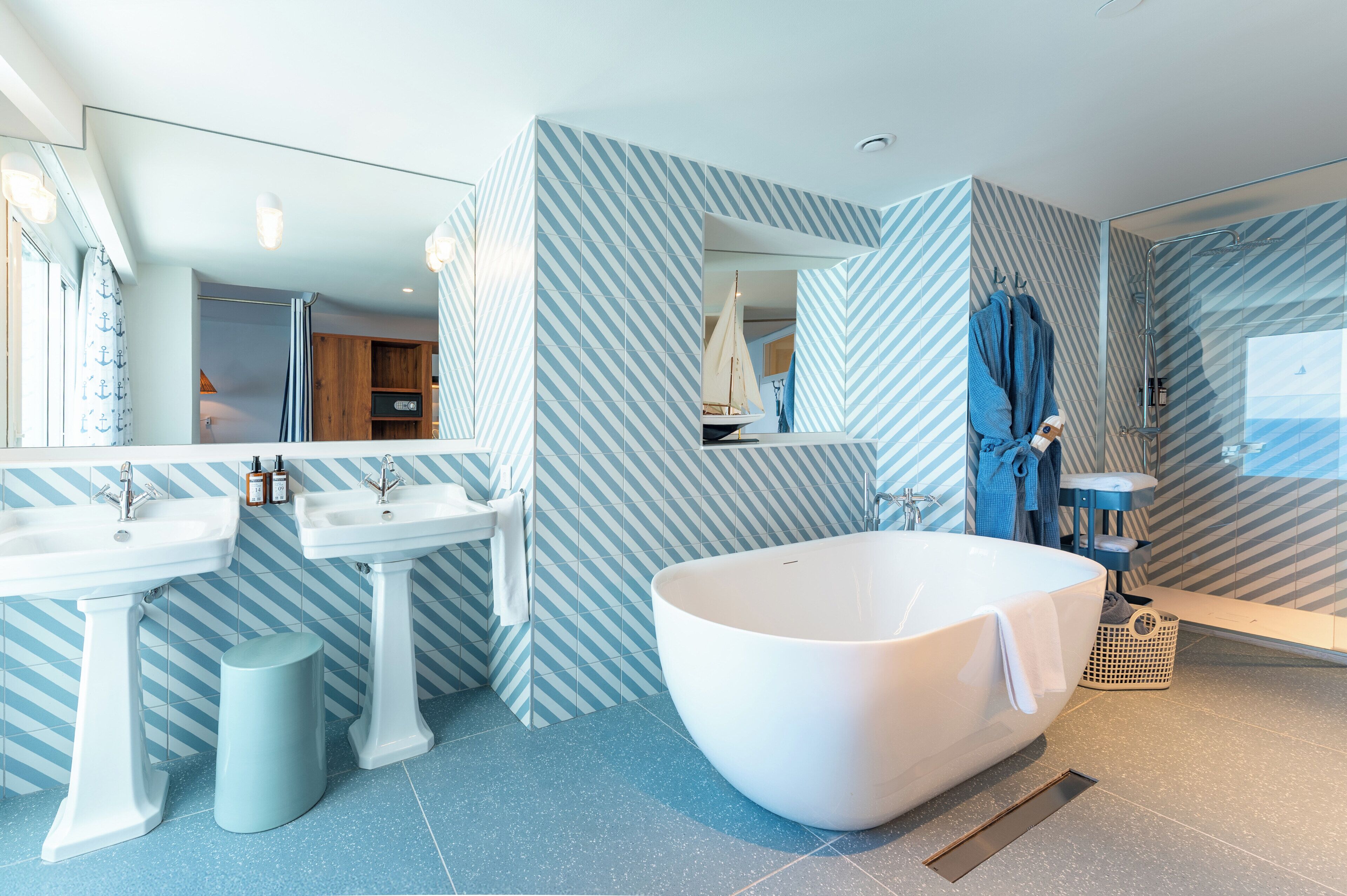 Une salle de bain moderne avec deux vasques, une baignoire sur pieds et un grand miroir.