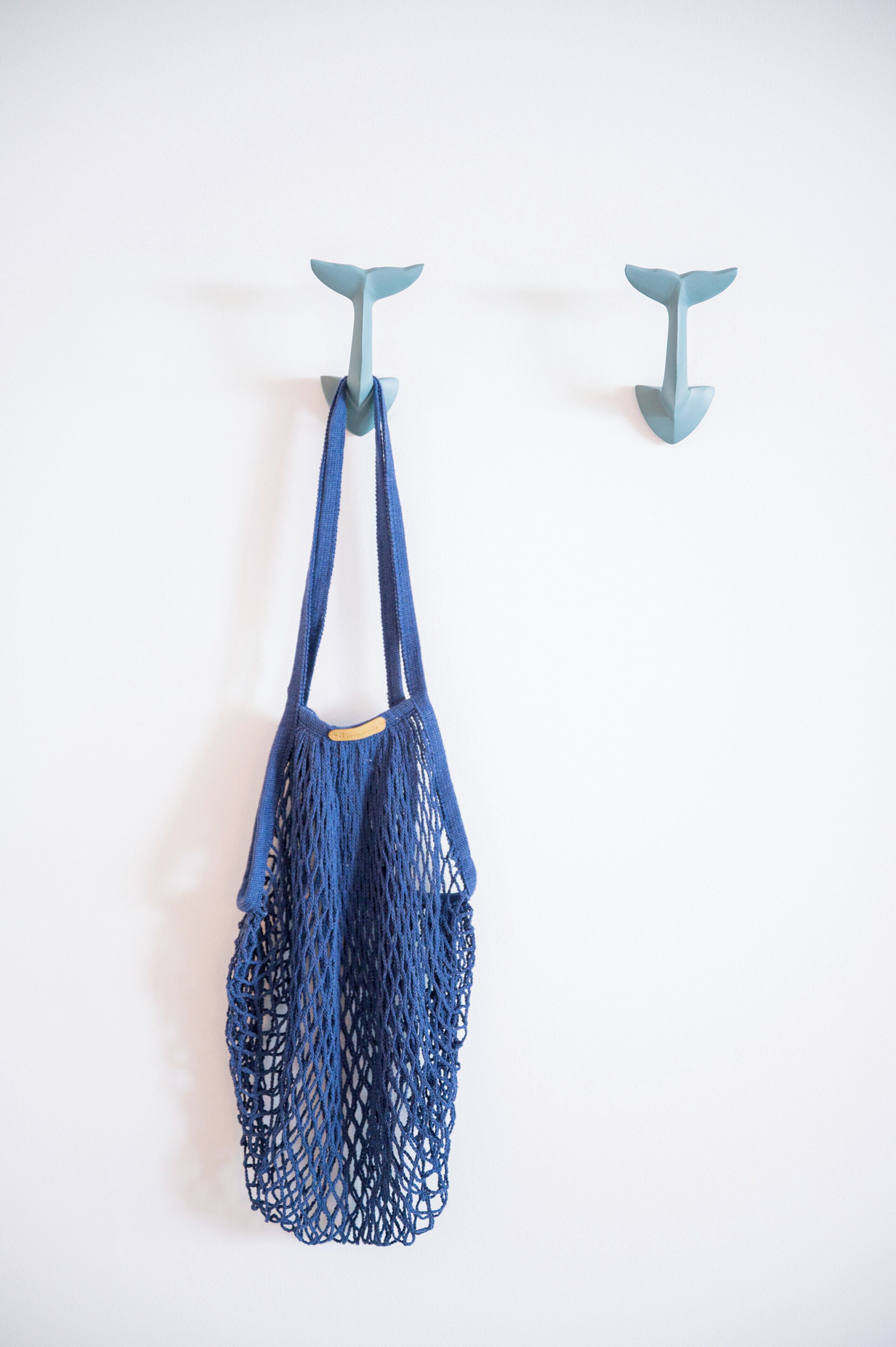 Una bolsa de malla azul colgada de un gancho en la pared.