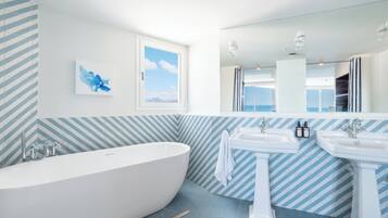 Een moderne badkamer met een vrijstaand bad, twee wasbakken en een grote spiegel.