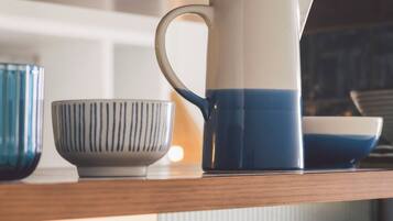 A shelf with a white and blue pitcher, a striped bowl, and a blue and white bowl.