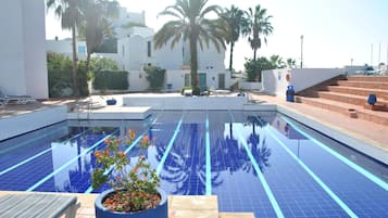 Una piscina al aire libre, sombrillas, sillones reclinables de piscina