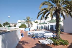 Una piscina al aire libre, sombrillas, sillones reclinables de piscina